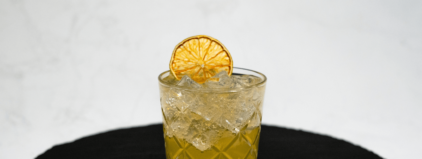 Moscow Mule Cocktail close up showing top half of glass with ice and dried lime slice resting on the top. 