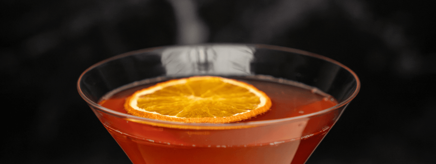 top of martini glass with red liquid and dried orange slice garnish on a black background