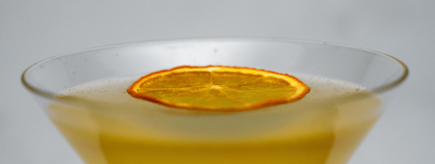 Close up of top of Tiki Orange Daiquiri cocktail showing dried orange slice garnish on a white background