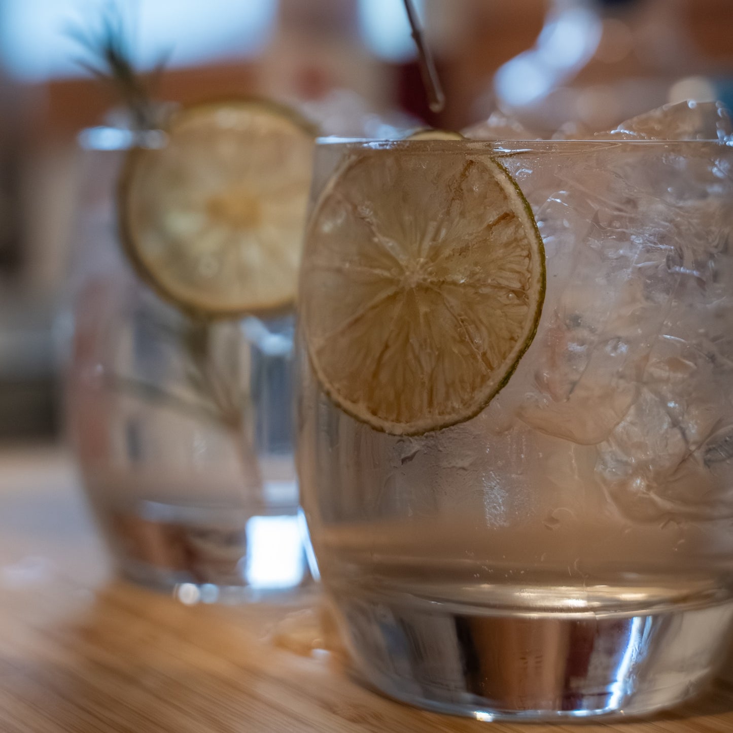 Close up of gin and tonic in glass with ice and dried lime slice.