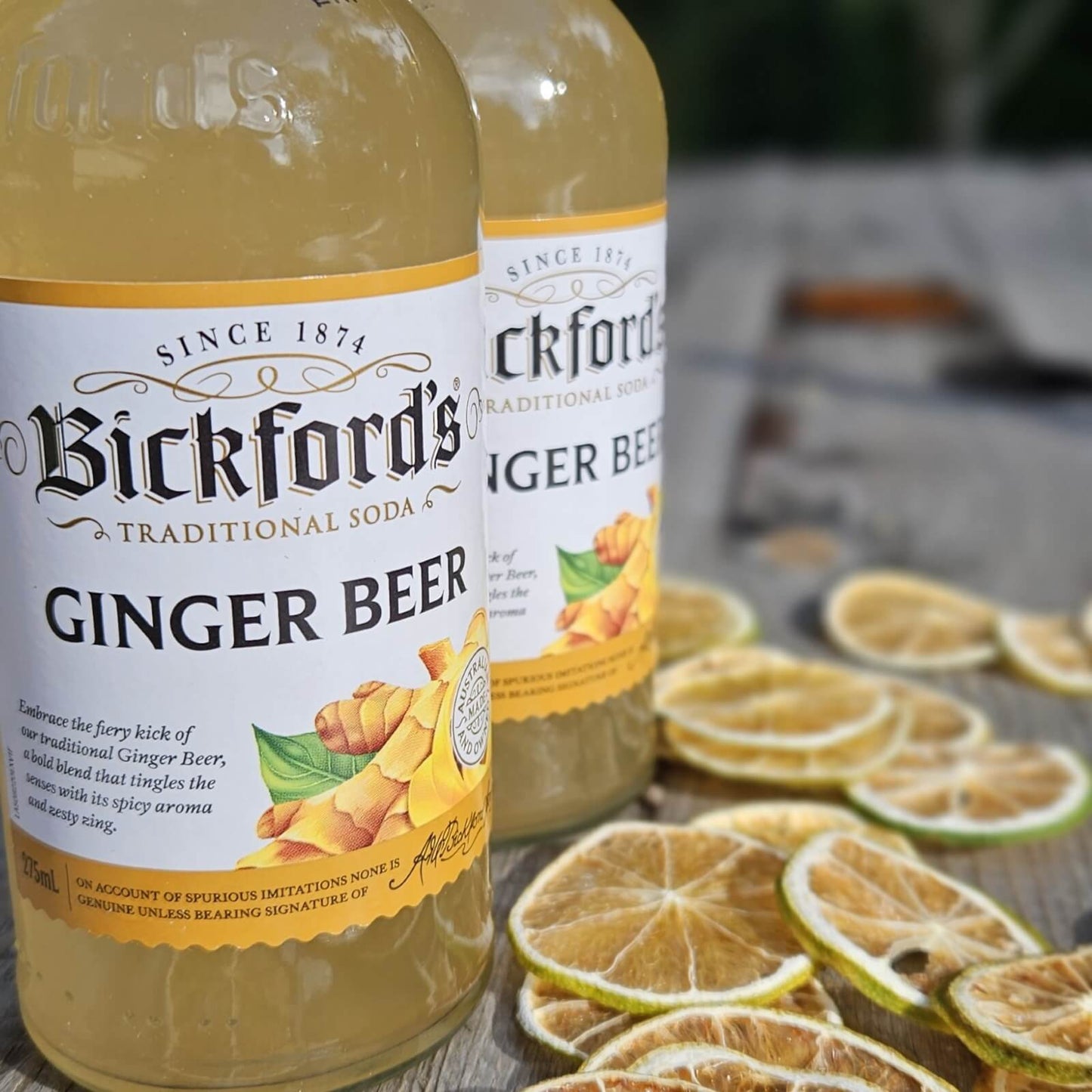 Two bottles of Bickford's Ginger Beer with lime slices on a wooden surface.