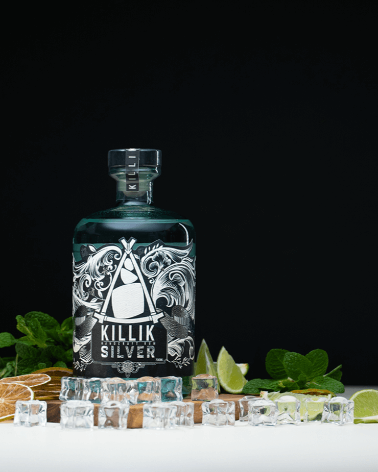 Killik solver bottle on a wooden board with mint, fresh limes and ice on a black background