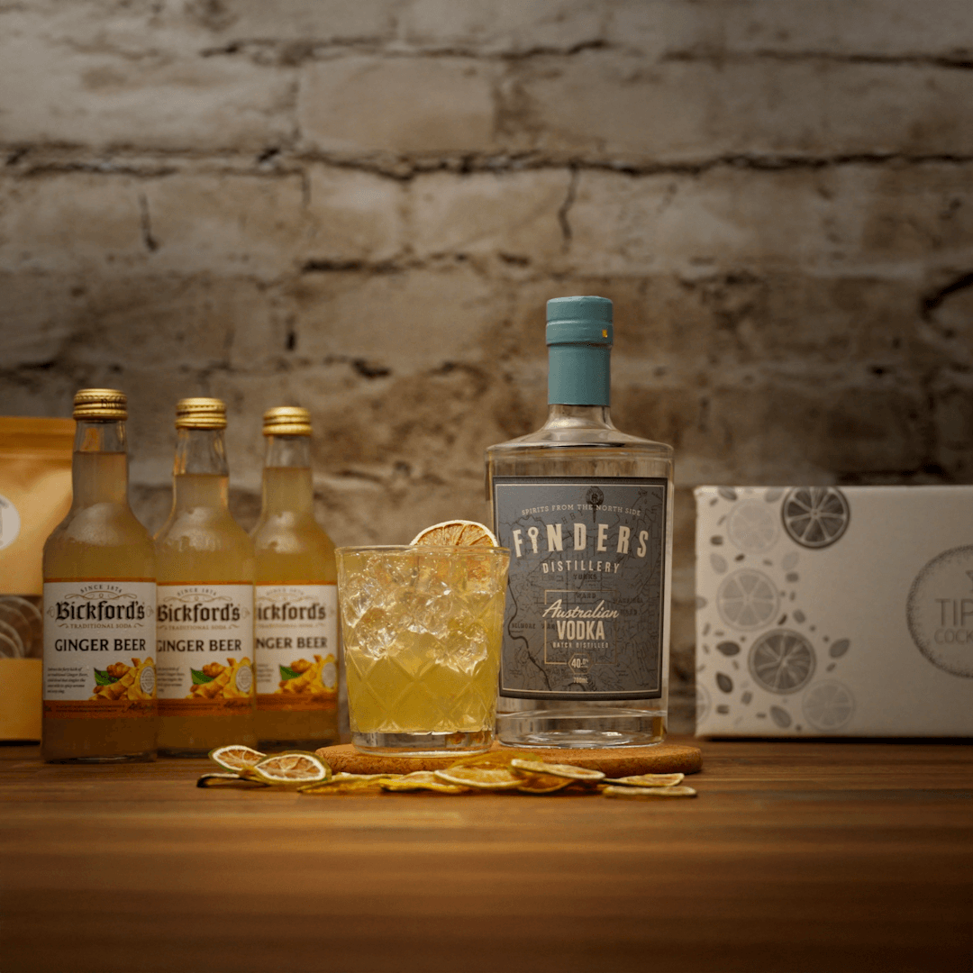 Moscow Mule Cocktail Kit showing kit contents including a bottle of Finders Distillery Australian Vodka with a Bickford's ginger beer bottles on a wooden surface against a brick wall.