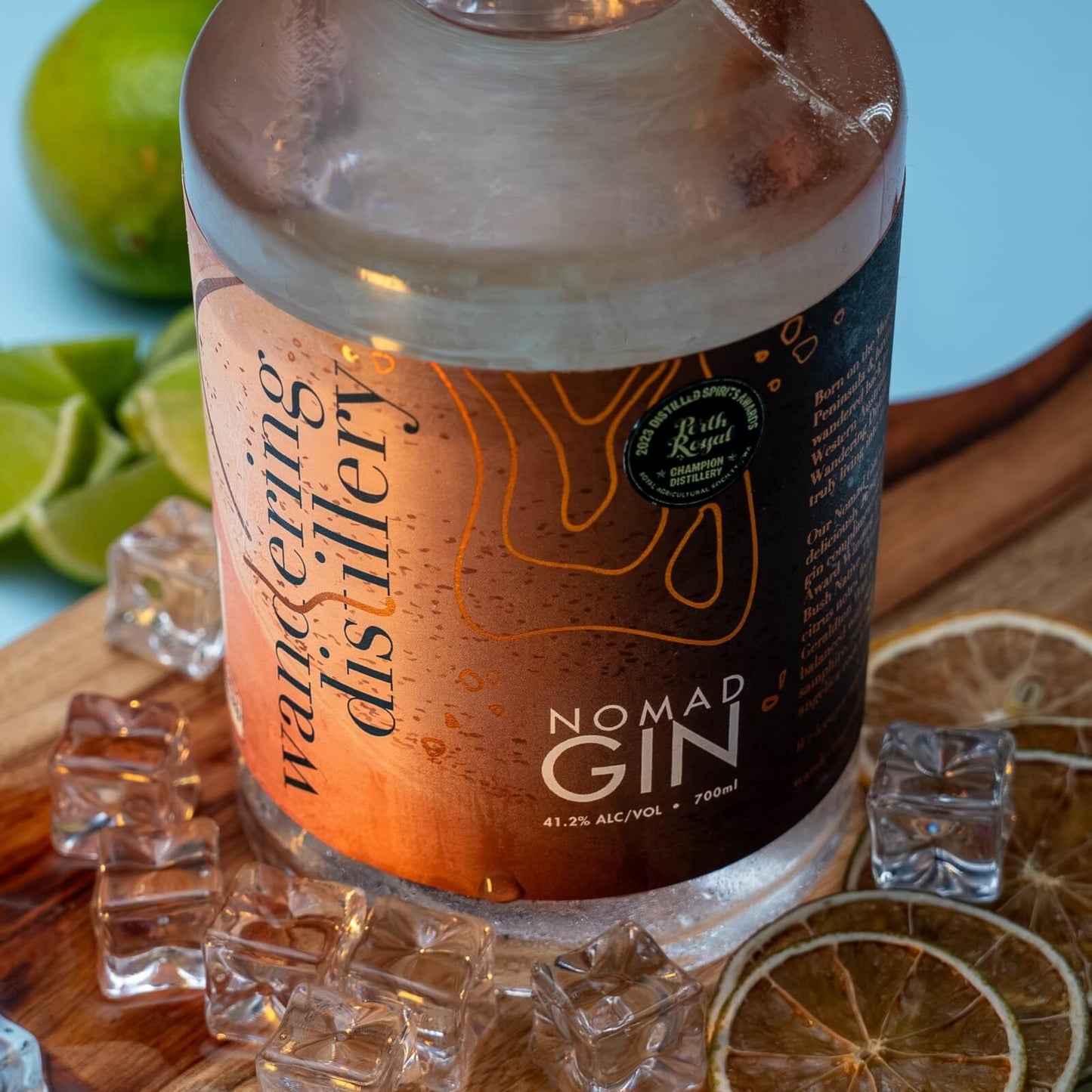 Close up of Nomad Gin bottle of wooden board with ice and fresh lime.