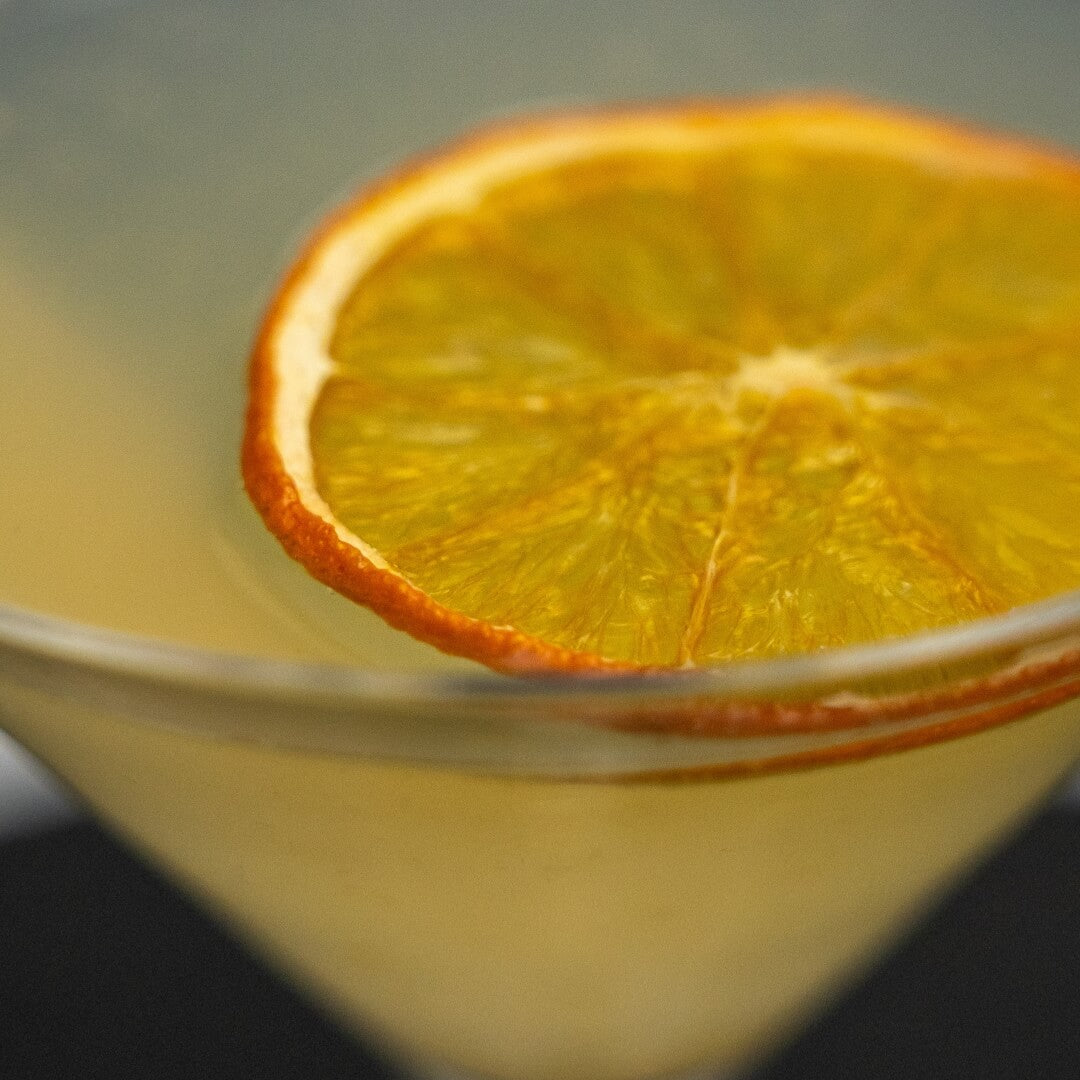 Close-up of a tiki orange daiquiri cocktail with an orange slice garnish on a dark background