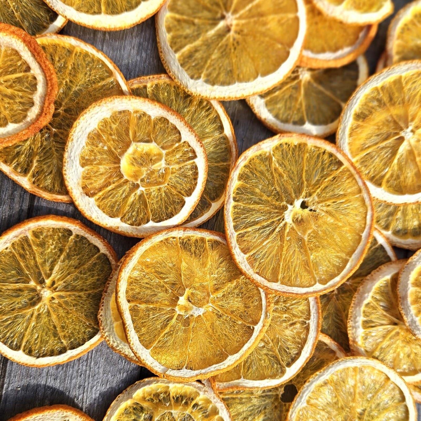 multiple dried orange slices on a wooden bench top