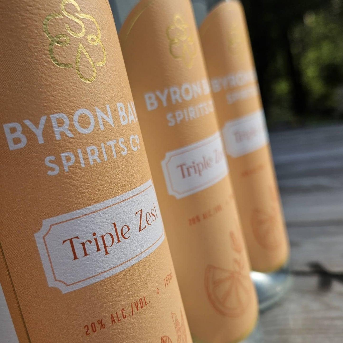 Close up of 3 bottles of Byron Bay Triple Zest Liqueur with a blurred background