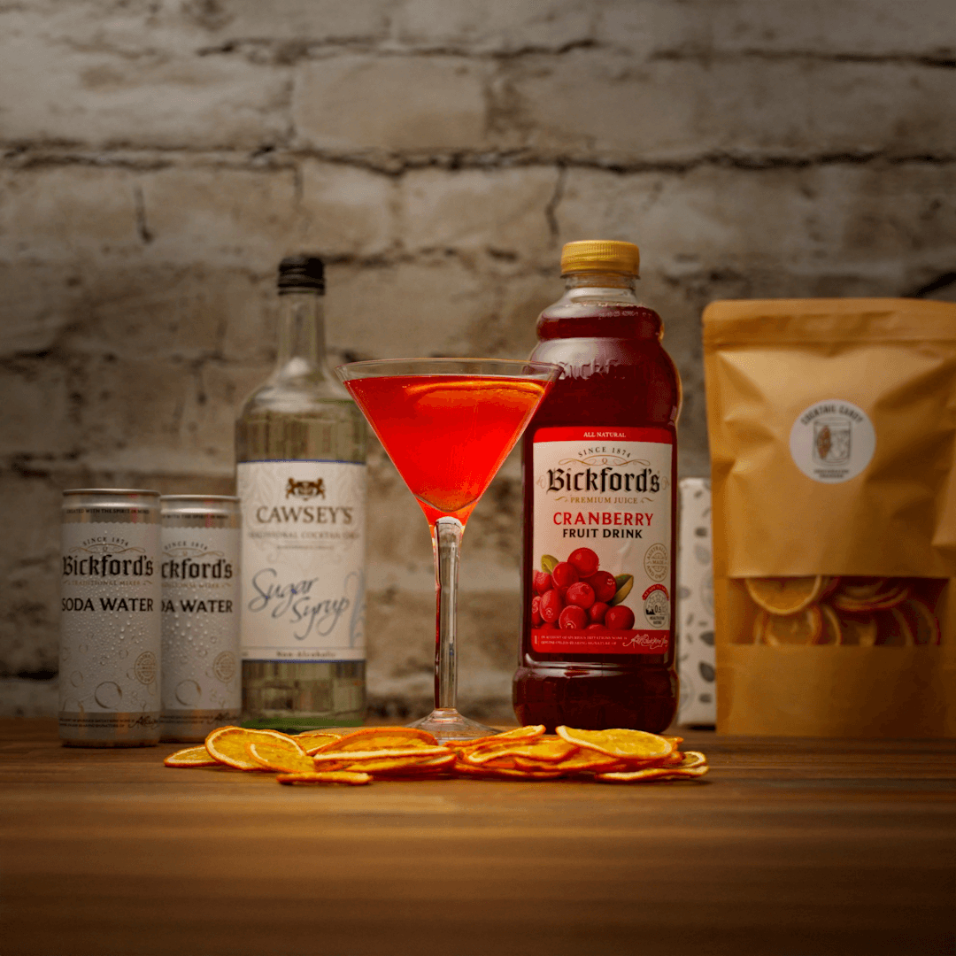 Mocktail with Bickford's cranberry juice and other ingredients on a wooden surface with a brick wall background.
