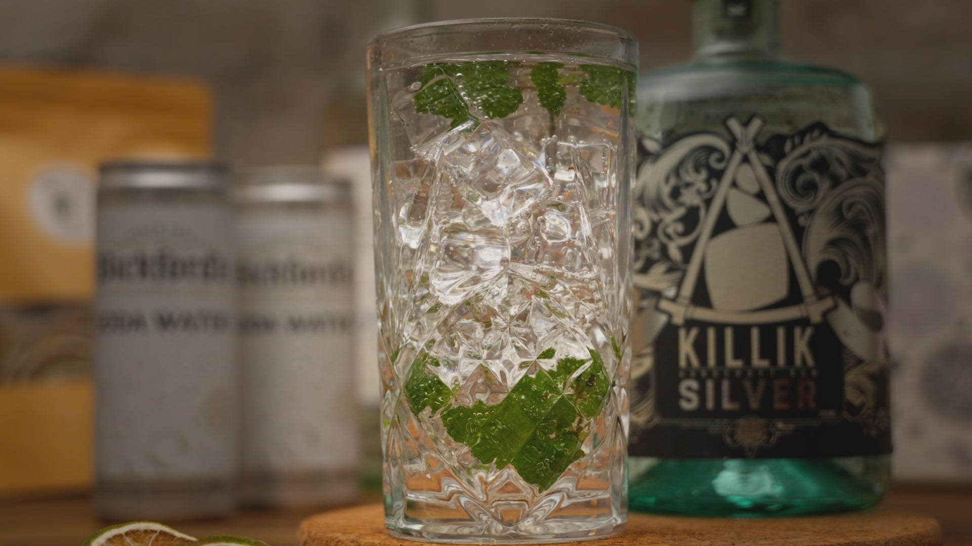 Video shows a close up of a mojito cocktail being garnished with a dried lime, zooming out to show Mojito Cocktail Kit supplies including a bottle of killik silver rum, bickfords soda water and dried lime slices. Video zooms back in to show a reverse of the garnishing action