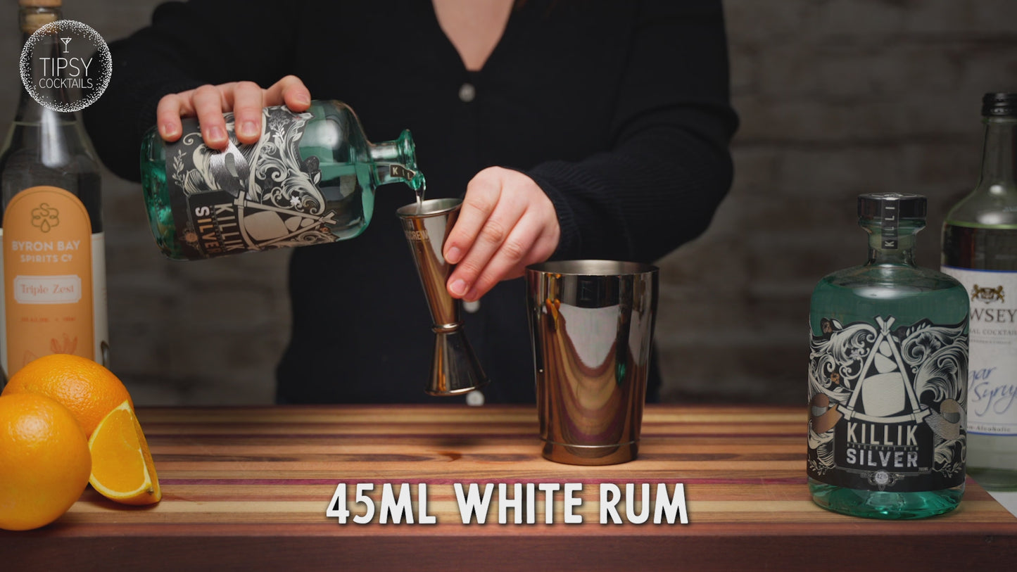 Video shows the recipe and making of a Tiki Orange Daiquiri. Start by adding 45ml of white rum into cocktail shaker, 15ml Triple Sec, 15ml sugar syrup, good squeeze of fresh orange juice. Fill shaker cup with ice and put lid on. shake, shake shake. Strain all liquid into martini glass and garnish with dried orange slice. Enjoy fresh or, enjoy frozen by adding all ingredients to a blender with 1 cup of ice. Frozen and fresh daiquiris are shown side by side at the end. 