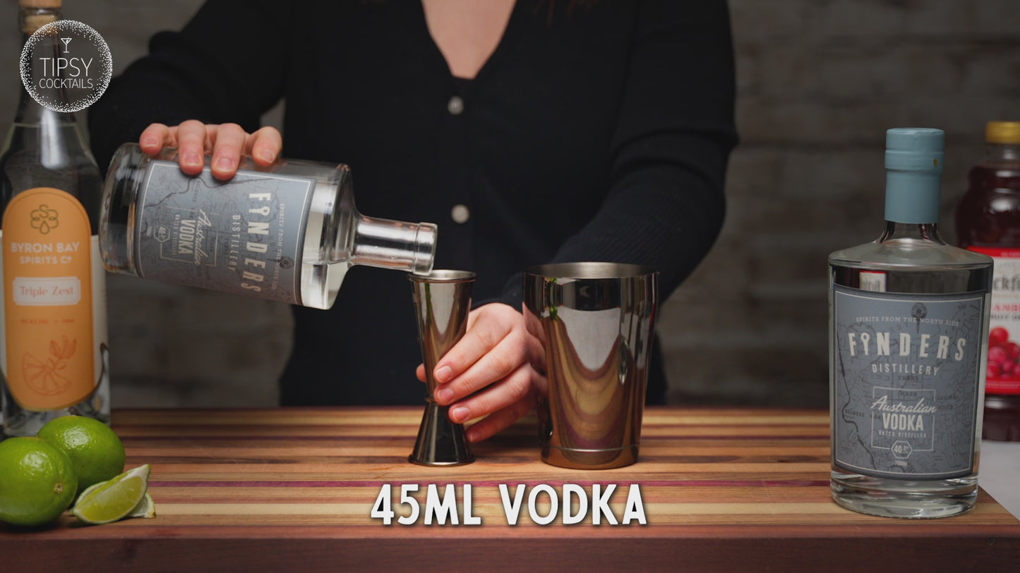 Recipe video showing how to make a cosmopolitan cocktail. Starting with adding 45ml vodka to shaker, 30ml cranberry juice, 15ml triple sec and a good squeeze of lime juice. Fill shaker with ice and shake shake shake! Strain all liquid into a martini glass and garnish with a dried lime slice.